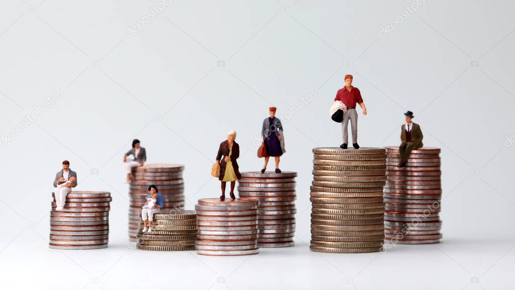 Miniature people standing on piles of different heights of coins. Income and economic inequality concept.