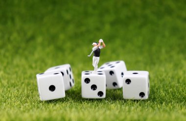 Beyaz zarlarda sallanan minyatür bir golfçü.