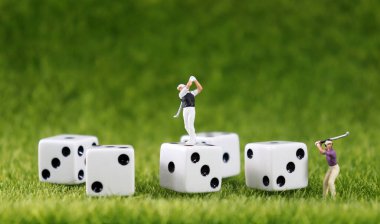 Two miniature golfers and five white dice with a lawn background. clipart