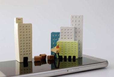 Akıllı telefonların üstünde minyatür evler ve minyatür kuryeler..