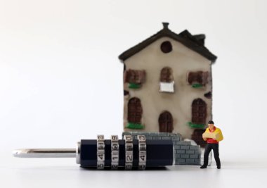 Minyatür bir evin önünde kilitli minyatür bir kurye..