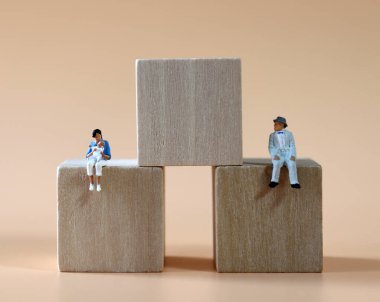 Minyatür insanlar tahta blokta uzaktan oturuyorlar..