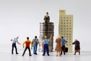 Çok sayıda minyatür insan minyatür binaların ve madeni para yığınlarının önünde toplandı..