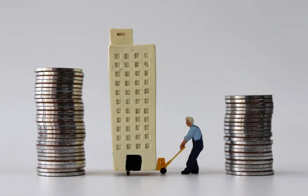Мініатюрна Людина Яка Переміщує Мініатюрну Будівлю Від Купи Високих Монет — стокове фото