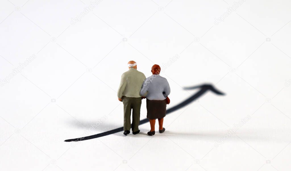 The back of a miniature old couple standing on a black arrow.