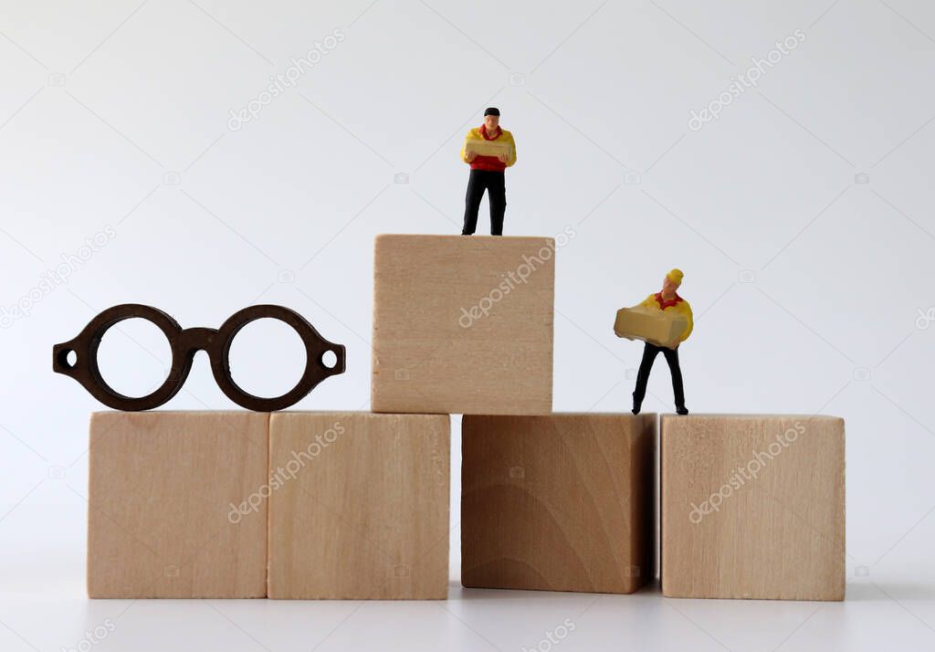 Miniature couriers standing on wooden blocks and miniature eyeglasses.