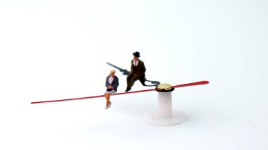 Minyatür adam ve kadın bir saatin üzerinde oturuyorlar. Cinsiyet eşitsizliği kavramları.