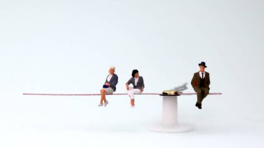 Minyatür adam ve kadın bir saatin üzerinde oturuyorlar. Cinsiyet eşitsizliği kavramları.