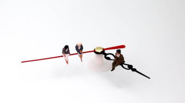 Minyatür adam ve kadın bir saatin üzerinde oturuyorlar. Sürekli cinsiyet farklılığı kavramı.