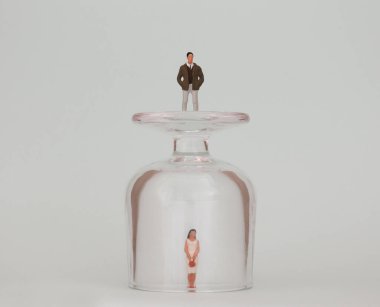 Cam bardakta minyatür bir kadın ve cam bardağın üstünde minyatür bir adam. Kadınlarda var olan görünmez tanıtım kavramı.