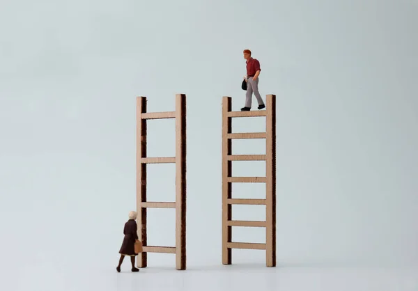 Wooden ladders and miniature people. The concept of difficulty in promoting women to work.