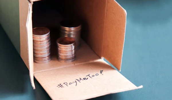 #PayMeToo as a new campaign to close the wage gap between men and women. An open pile of paper boxes and coins.