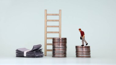 Minyatür bir adam bozuk para yığınının üzerinde yürüyor. Gelir açığı kavramı.