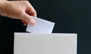 Oy sandığına oy veren bir kadının eli. Seçimlere katılım ve hak etkinlikleri konsepti.