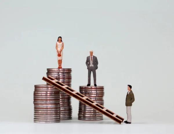 The concept of women's leadership. A miniature woman standing on top of a pile of the highest coins.