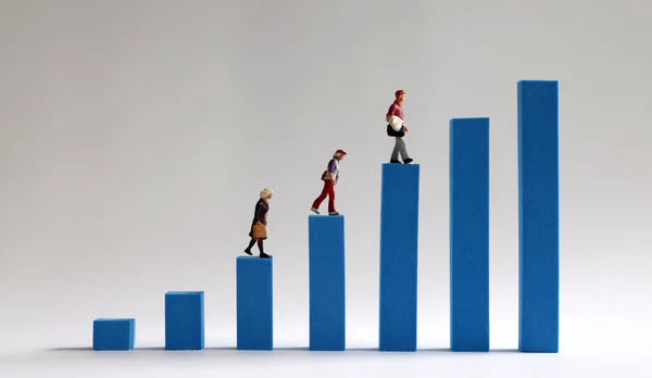 Three miniature people walking on a blue bar graph. The concept of income gap between individuals.