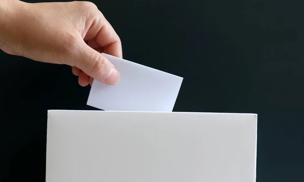 Oy sandığına oy veren bir kadının eli. Seçimlere katılım ve hak etkinlikleri konsepti.