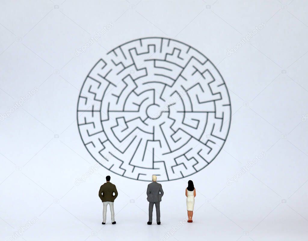 Two miniature men and a miniature woman watching the maze.