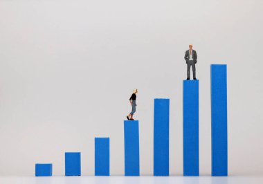 Minyatür bir adam ve minyatür bir kadın mavi çizginin farklı yüksekliklerinde duruyorlar.. 