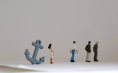 Üç minyatür adam ve gri bir çapa ve minyatür bir kadın. Kadınların işyerinde terfi etmelerine ilişkin kısıtlayıcı bir kavram..