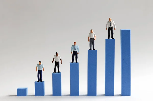 The concept of racial income gap. Miniature people standing on a bar graph bar.