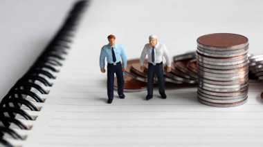 Çalışma ve gelir için planlama kavramları. Minyatür adamlar ve madeni paralar.