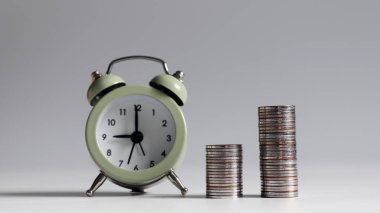 Alarm saatinden farklı yükseklikte iki bozuk para yığını..