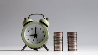 Çalar saatle aynı yükseklikte iki bozuk para yığını..