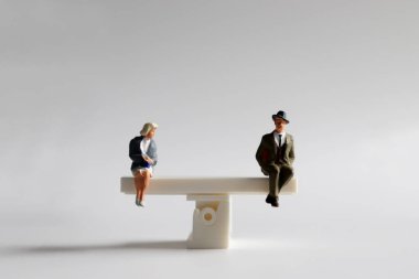 Kadın ve erkek için fırsat eşitliği kavramı. Minyatür bir adam ve kadın mini bir tahterevallinin üzerinde oturuyor..
