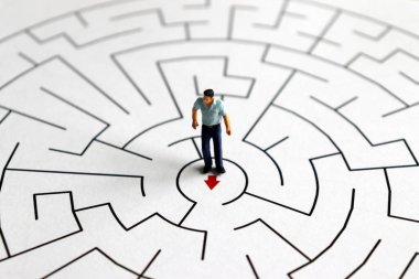 Elinde okla labirentin ortasında duran minyatür bir adam..