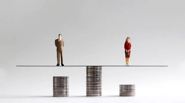 The concept of gender pay gap. Miniature people with stack of coins.
