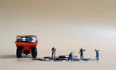 Minyatür işçiler bir kamyona bozuk para yüklüyorlar. İş gücü ve sermaye arasındaki ilişki kavramı.