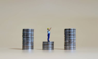 Madeni para yığınları arasında duran ve bozuk paraların tepesini gösteren minyatür bir adam..