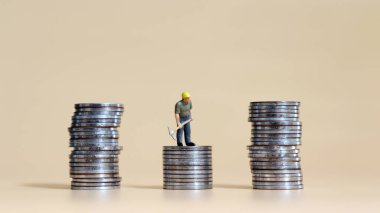 Bir minyatür işçi ve üç bozuk para yığını..