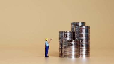 Bir yığın para ve onları gösteren minyatür bir adam..