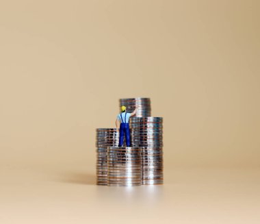 Bozuk para yığınları olan minyatür bir adam..