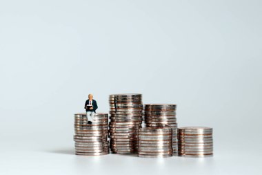 Bir yığın bozuk para ve üzerinde yaşlı bir adamın minyatürleri oturuyor..