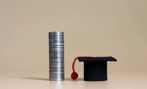 A pile of coins and miniature graduation cap. The concept of student loans.