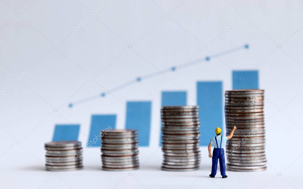 A miniature man pointing at a graph and a graph with four pile of coins.