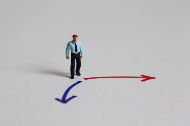 İki renkli yönün önünde duran minyatür bir adam..