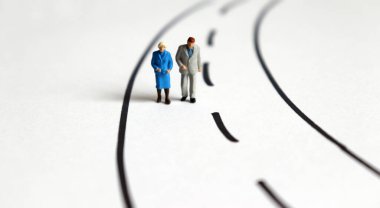 İki şeritli yolda yürüyen minyatür yaşlı insanlar..