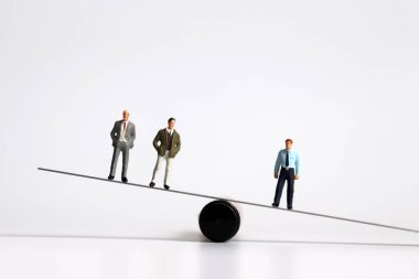 Tahterevallinin üzerinde duran minyatür adamlar.