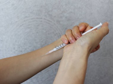 Koluna ilaç enjekte eden bir kadın..