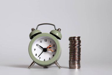 Saatin üstünde minyatür insanlar ve madeni paralar asılı..