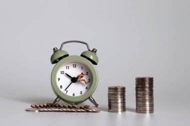 Saatin üstünde minyatür insanlar ve madeni paralar asılı..