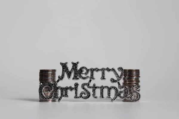 Text Merry Christmas and two pile of coins.