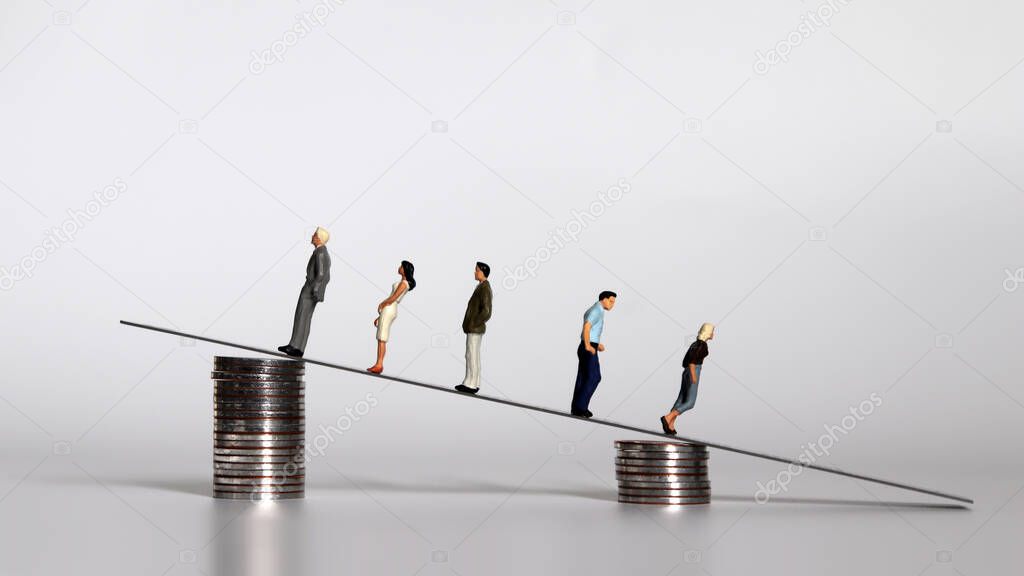 Miniature people with a pile of coins. The concept of the gap between rich and poor.