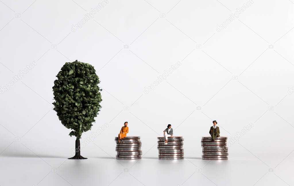 The concept of gender equality in wages. A miniature men and women sitting on top of a pile of coins of the same height.