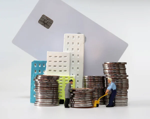 Miniature people carrying a pile of coins. Pile of coins and credit card.