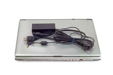 Beyaz arkaplanda elektrik şarj prizi olan eski dizüstü bilgisayar